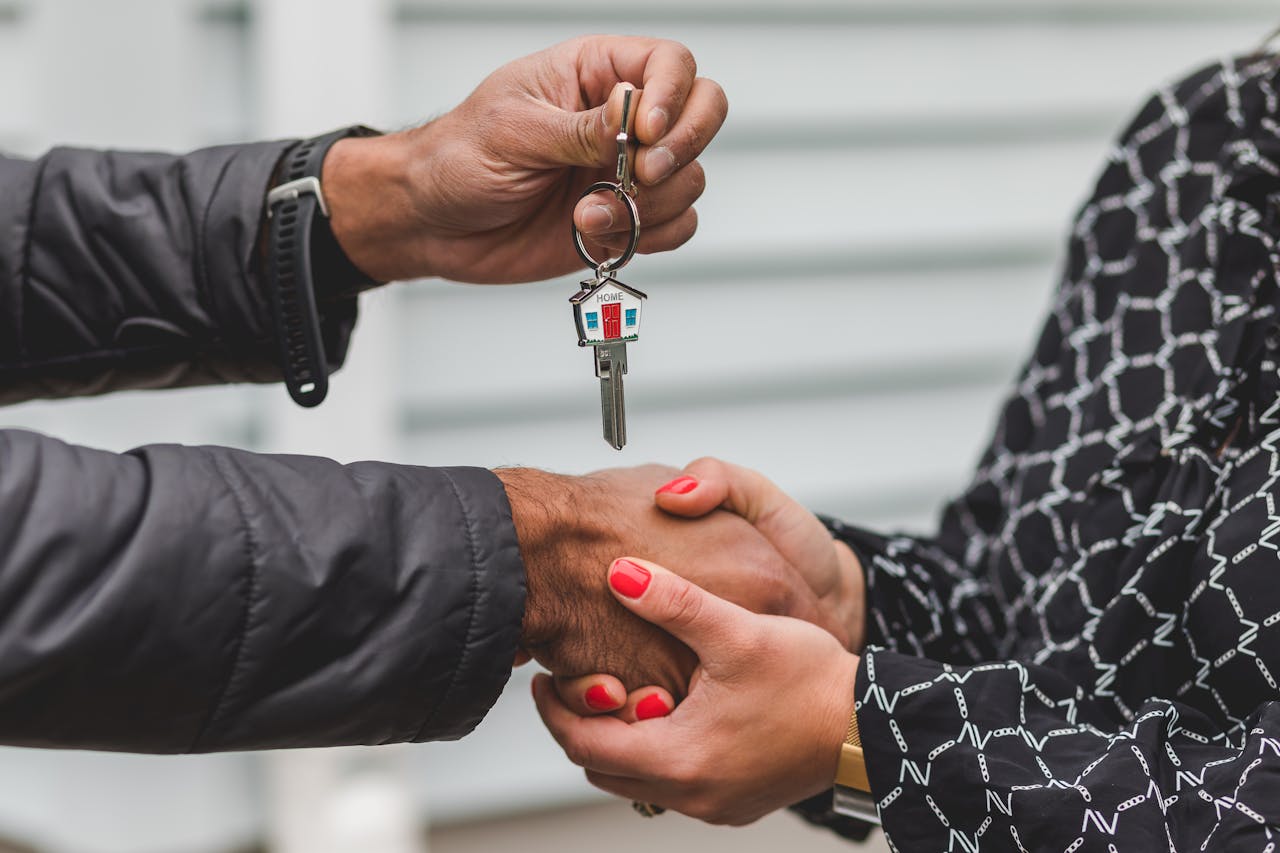 Mastering the First Impression: Your intriguing post title goes here Close-up of a realtor handing over a house key to a new homeowner, symbolizing ownership and investment.